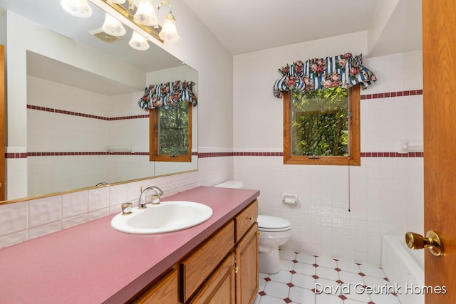 bathroom featuring toilet, vanity, and tile walls