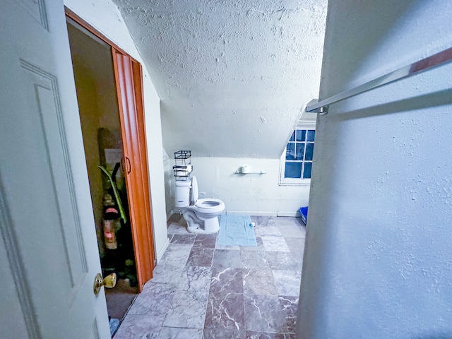 bathroom with a textured ceiling, toilet, and vaulted ceiling