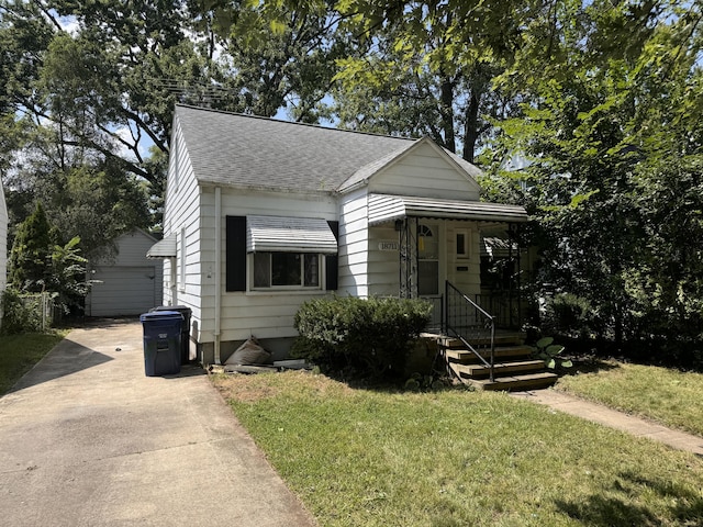 view of front of property featuring a front yard, a garage, and an outdoor structure