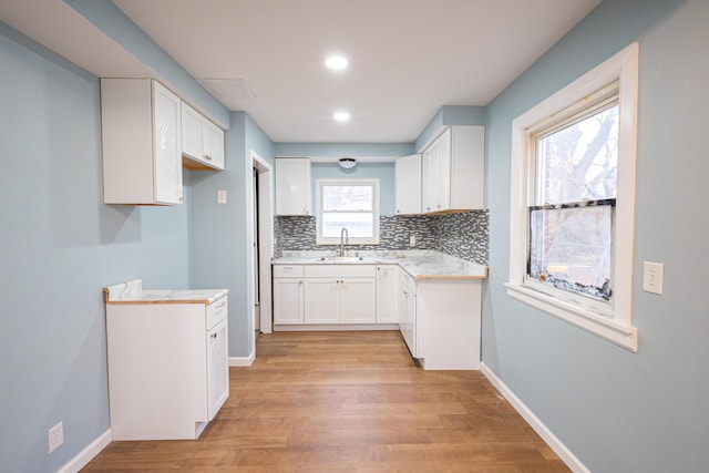 kitchen featuring decorative backsplash, a healthy amount of sunlight, white cabinets, and sink