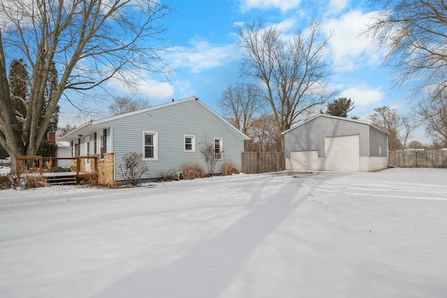 snow covered property with a garage and an outbuilding