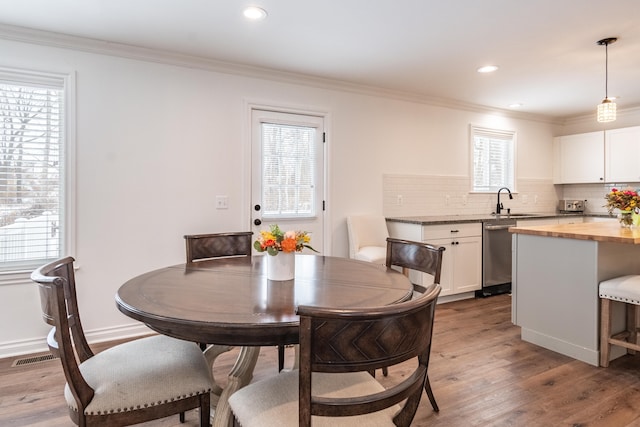 dining room with sink, light hardwood / wood-style flooring, and ornamental molding