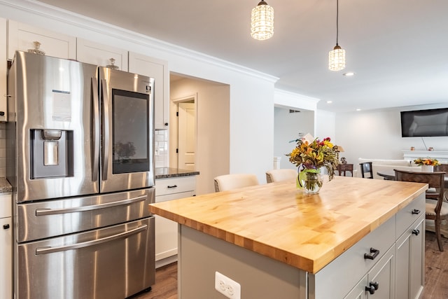 kitchen featuring pendant lighting, white cabinets, stainless steel fridge with ice dispenser, butcher block countertops, and a center island