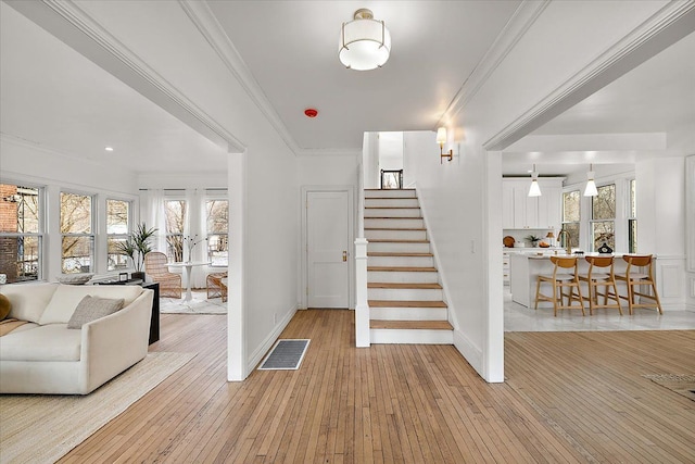 stairs with ornamental molding, wood-type flooring, and sink