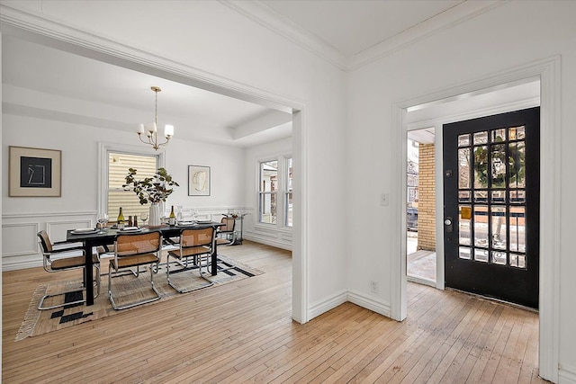 entryway featuring crown molding, light hardwood / wood-style flooring, and a notable chandelier