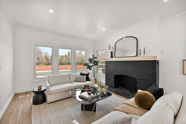 living room featuring crown molding, hardwood / wood-style flooring, and a tiled fireplace