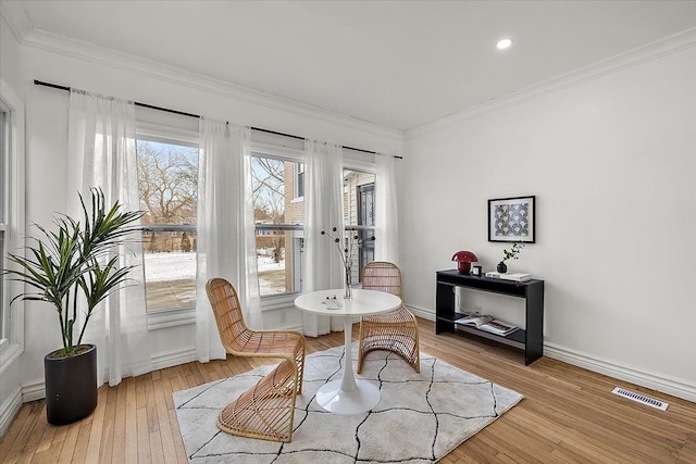 living area with crown molding and light wood-type flooring