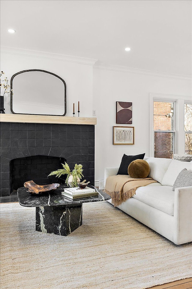 living room with a tile fireplace and crown molding