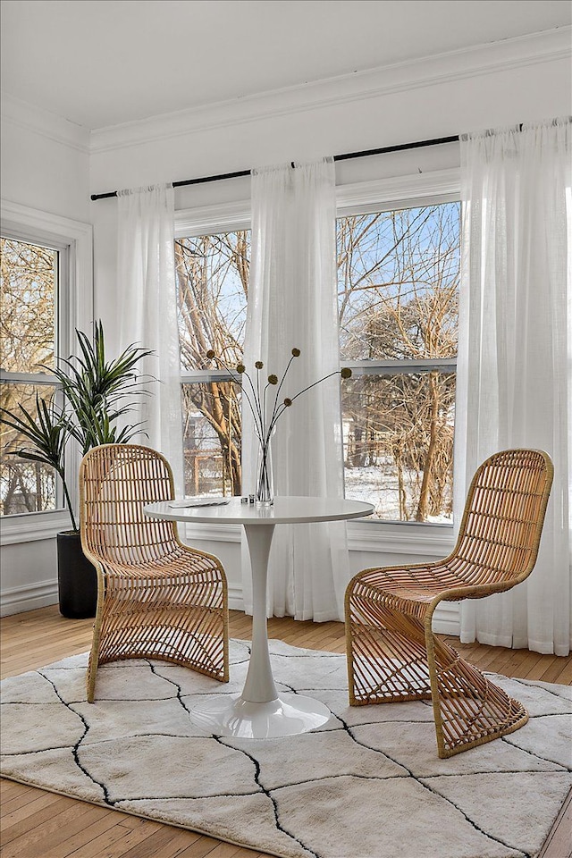 living area featuring a healthy amount of sunlight, ornamental molding, and light hardwood / wood-style flooring