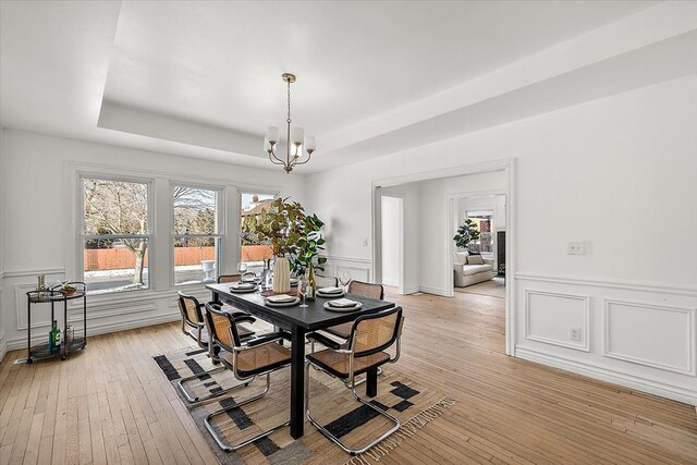 dining room with a tray ceiling, a wealth of natural light, and light wood-type flooring