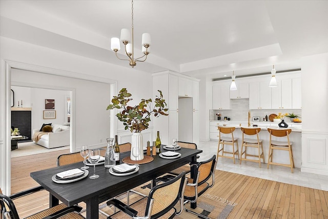 dining space with sink, a chandelier, and light hardwood / wood-style floors