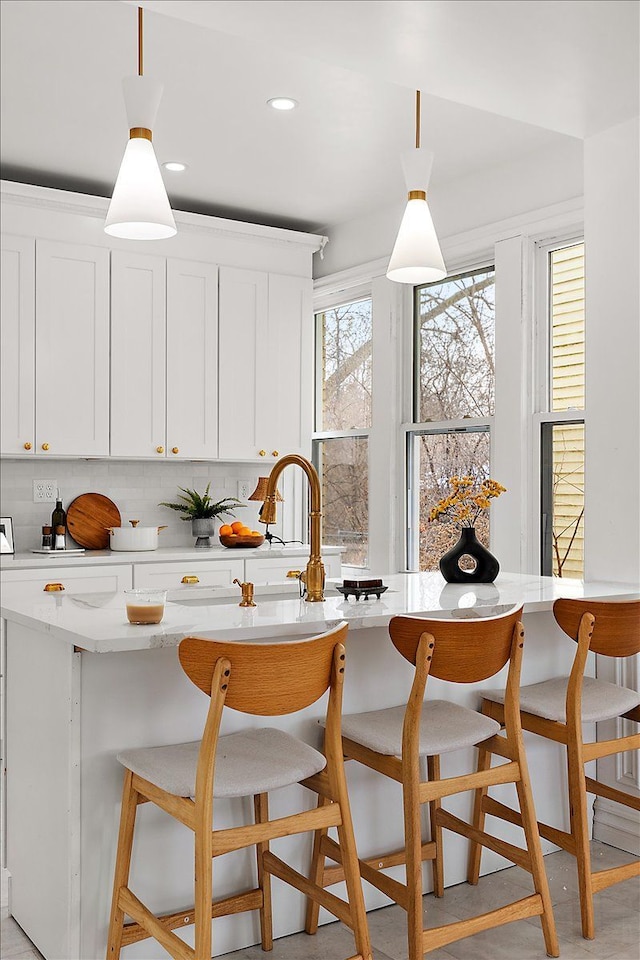 kitchen featuring tasteful backsplash, white cabinetry, pendant lighting, and a kitchen breakfast bar