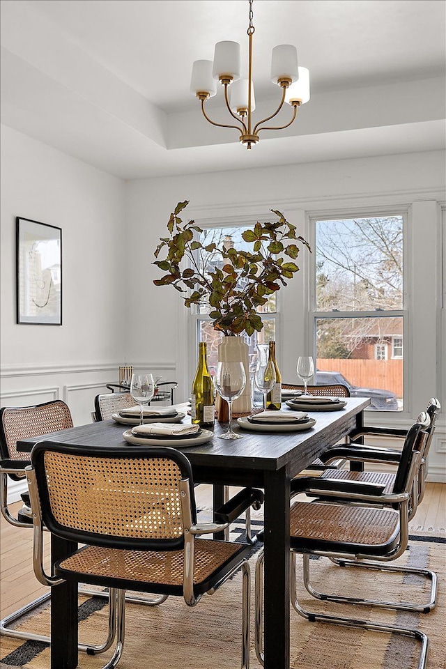 dining space with hardwood / wood-style flooring, a notable chandelier, and a tray ceiling