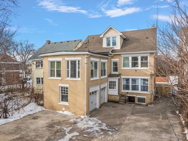 snow covered house featuring a garage and central AC unit