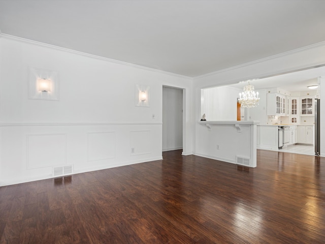 unfurnished living room with dark hardwood / wood-style floors, crown molding, and a notable chandelier