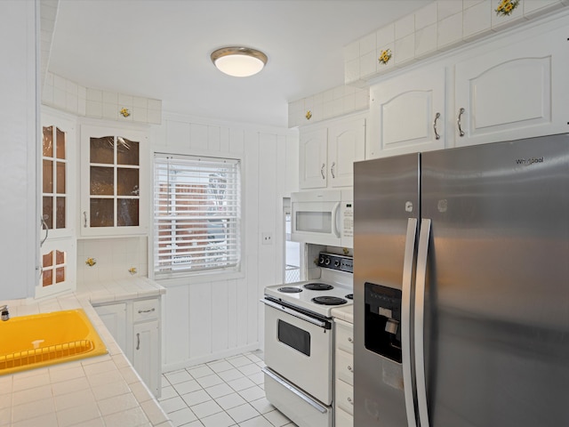 kitchen featuring white appliances, white cabinets, sink, tile countertops, and light tile patterned floors