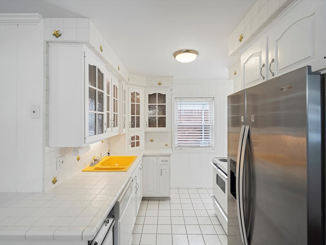 kitchen featuring light tile patterned floors, white cabinetry, tile countertops, white appliances, and sink