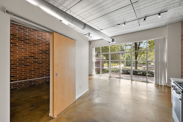 unfurnished room featuring brick wall and concrete flooring