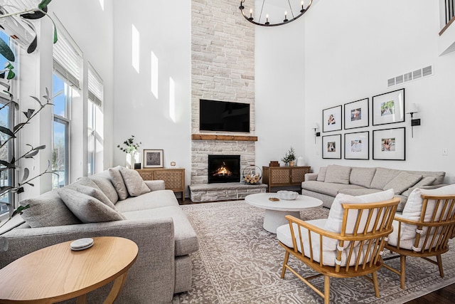 living room featuring a fireplace, a chandelier, wood-type flooring, and a high ceiling