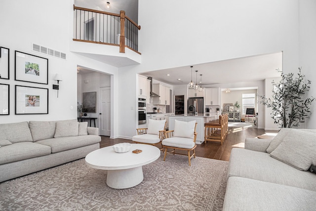 living room featuring a high ceiling, dark wood-type flooring, and sink