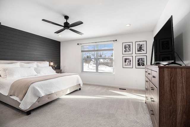 carpeted bedroom featuring ceiling fan and wood walls