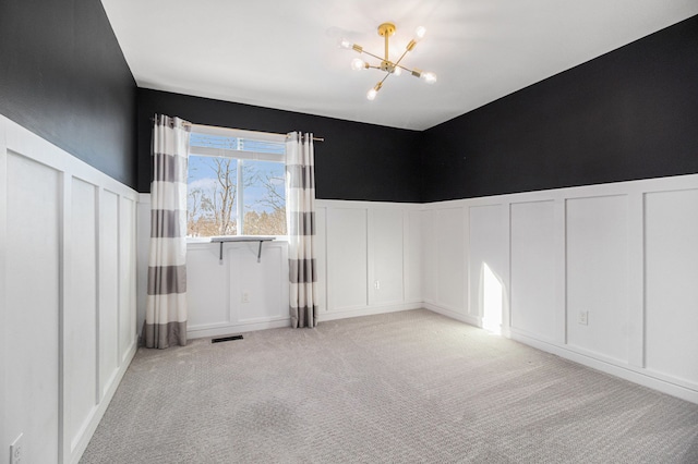 empty room featuring light colored carpet and a chandelier