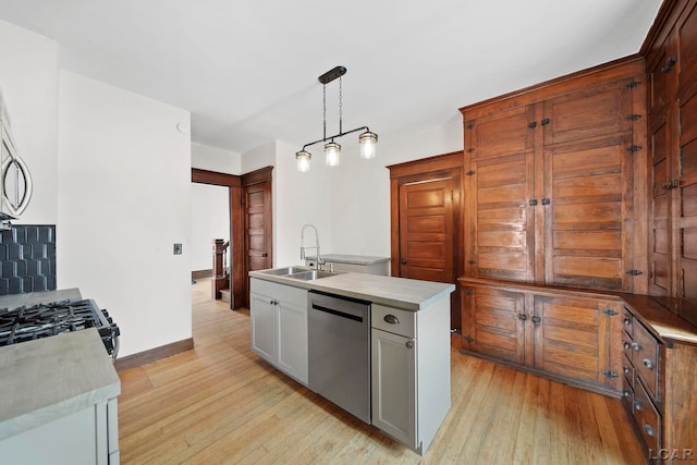 kitchen with white cabinetry, a kitchen island with sink, decorative light fixtures, stainless steel dishwasher, and sink