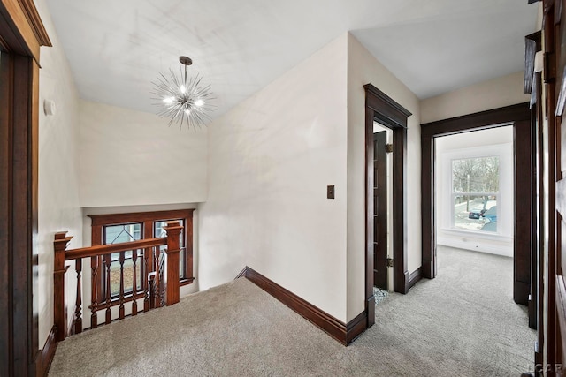 hallway with a chandelier and light colored carpet