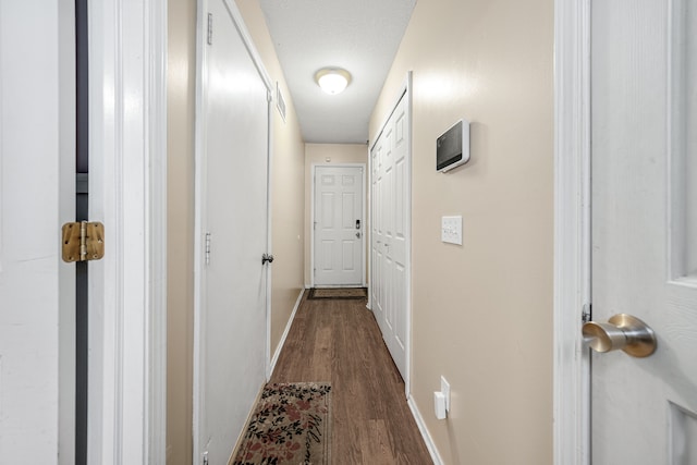 corridor with dark hardwood / wood-style floors and a textured ceiling