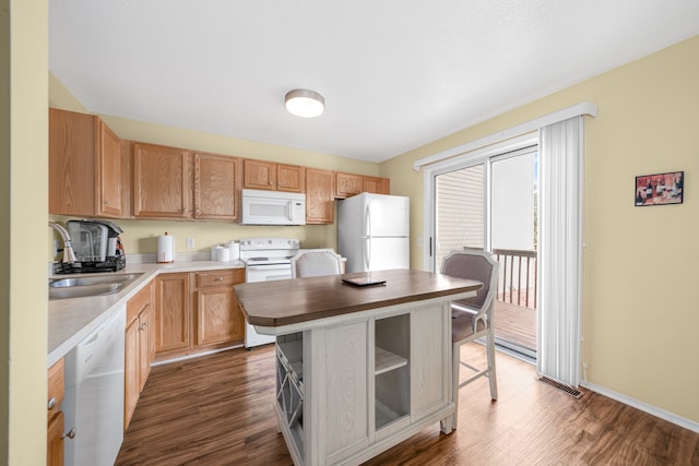 kitchen with white appliances, dark hardwood / wood-style floors, a center island, and sink