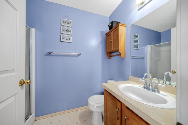 bathroom with vanity, a shower with door, and toilet