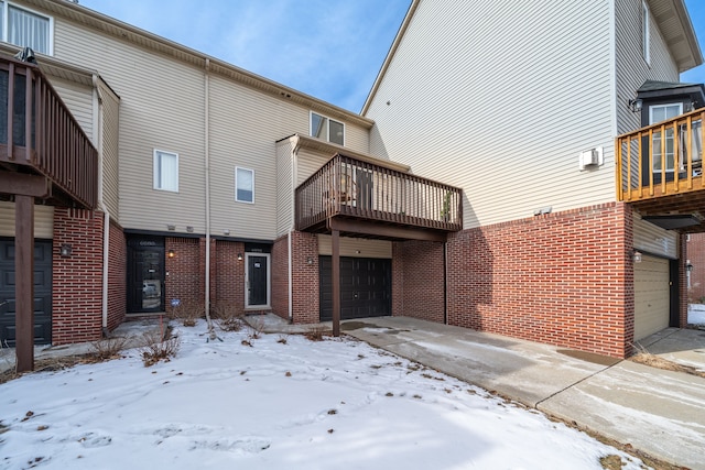 snow covered property featuring a balcony and a garage