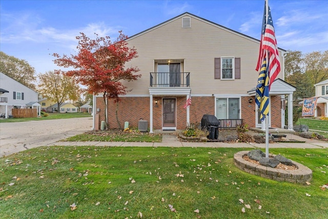 view of front of property featuring a balcony, a front yard, and central air condition unit