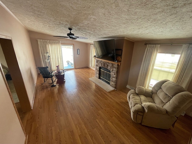 living room featuring wood-type flooring, ceiling fan, a textured ceiling, and a fireplace