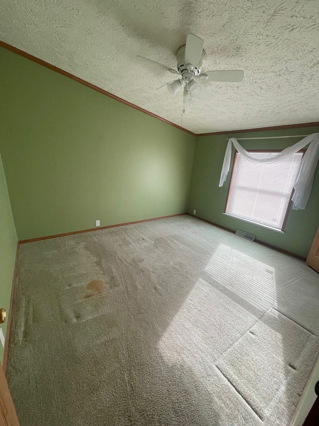 carpeted spare room with crown molding, ceiling fan, and a textured ceiling