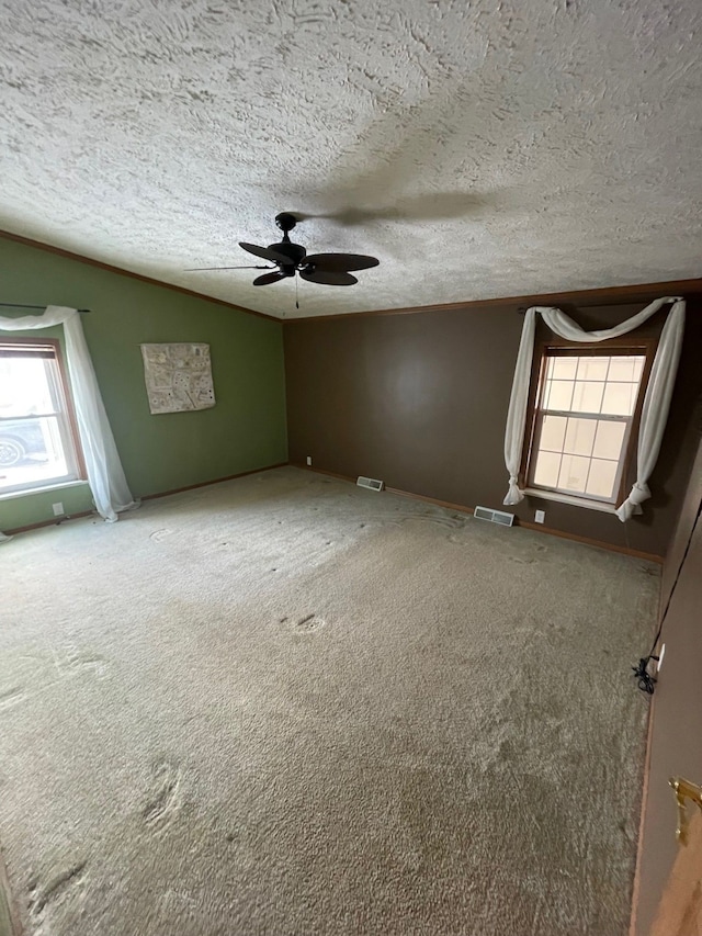 carpeted empty room with vaulted ceiling, crown molding, ceiling fan, and a textured ceiling