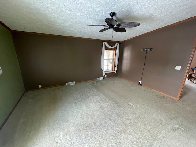 carpeted spare room with crown molding, ceiling fan, and a textured ceiling