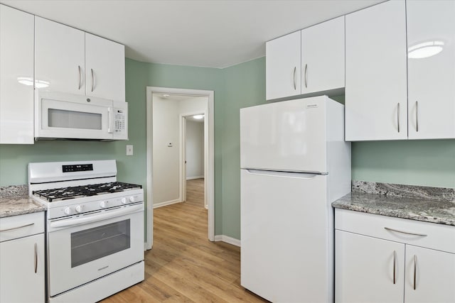 kitchen with light hardwood / wood-style floors, white cabinetry, white appliances, and light stone countertops