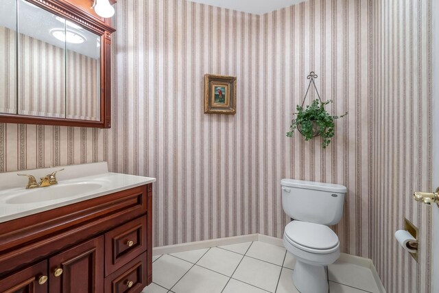 310 Sycamore St, Litchfield, MI 49252 - half bath featuring vanity, toilet, baseboards, wallpapered walls, and tile patterned floors