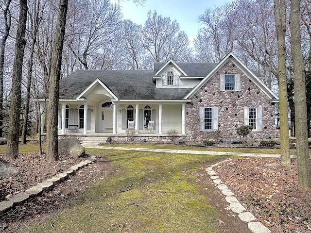 310 Sycamore St, Litchfield, MI 49252 - view of front of house featuring covered porch, stone siding, and a front lawn