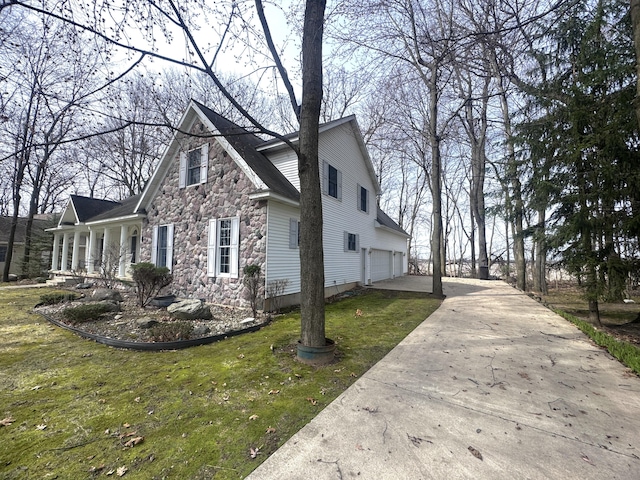 310 Sycamore St, Litchfield, MI 49252 - view of side of property featuring stone siding, driveway, a yard, and an attached garage