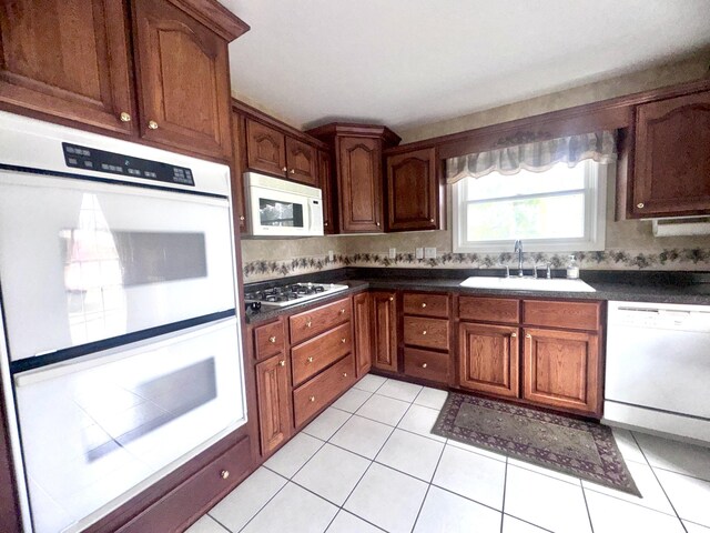 310 Sycamore St, Litchfield, MI 49252 - kitchen featuring white appliances, light tile patterned floors, decorative backsplash, a sink, and dark countertops