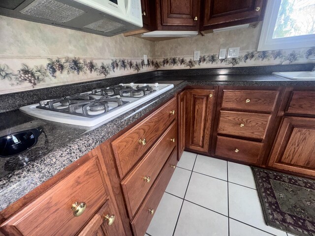 310 Sycamore St, Litchfield, MI 49252 - kitchen featuring white appliances, dark countertops, a sink, extractor fan, and light tile patterned floors