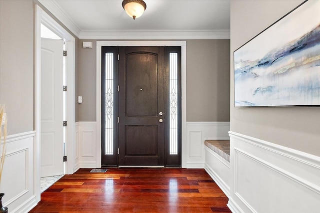 foyer featuring dark wood-type flooring, crown molding, and wainscoting