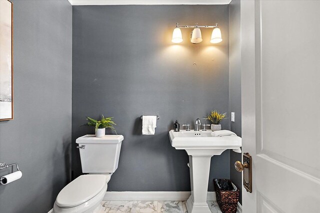 half bath featuring marble finish floor, toilet, and baseboards