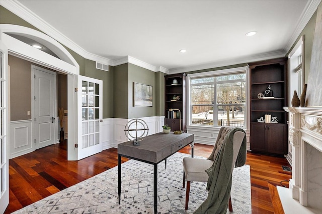 office space with ornamental molding, wainscoting, visible vents, and wood finished floors