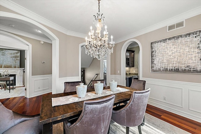 dining room featuring an inviting chandelier, visible vents, wood finished floors, and wainscoting