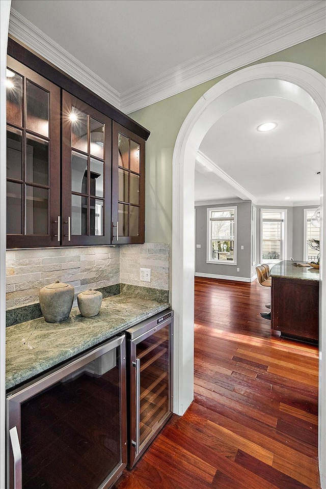 bar with arched walkways, beverage cooler, and a dry bar