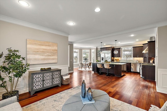 living room featuring a wainscoted wall, ornamental molding, dark wood-type flooring, and recessed lighting