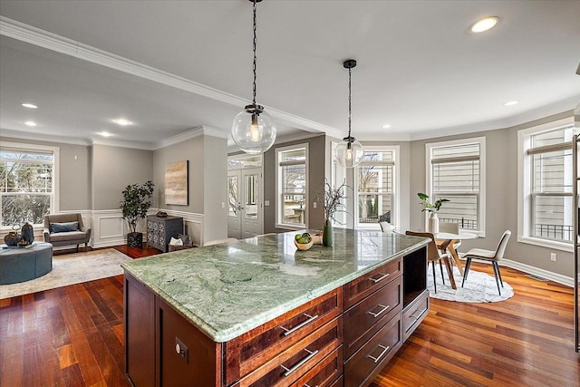 kitchen featuring dark wood-style floors, pendant lighting, ornamental molding, and light stone counters